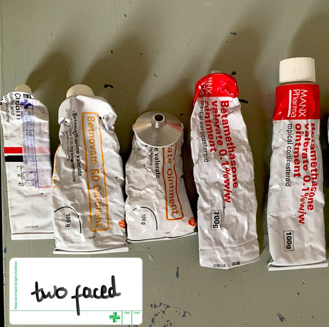 An image of 5 tubes of steroid creams. They are all crumbled and used. One is missing the lid. There is a pharmacy label in the corner of the photo which reads 'Two Faced'
